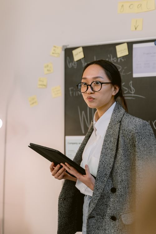 Free Asian woman in blazer holding tablet during a presentation in office. Stock Photo