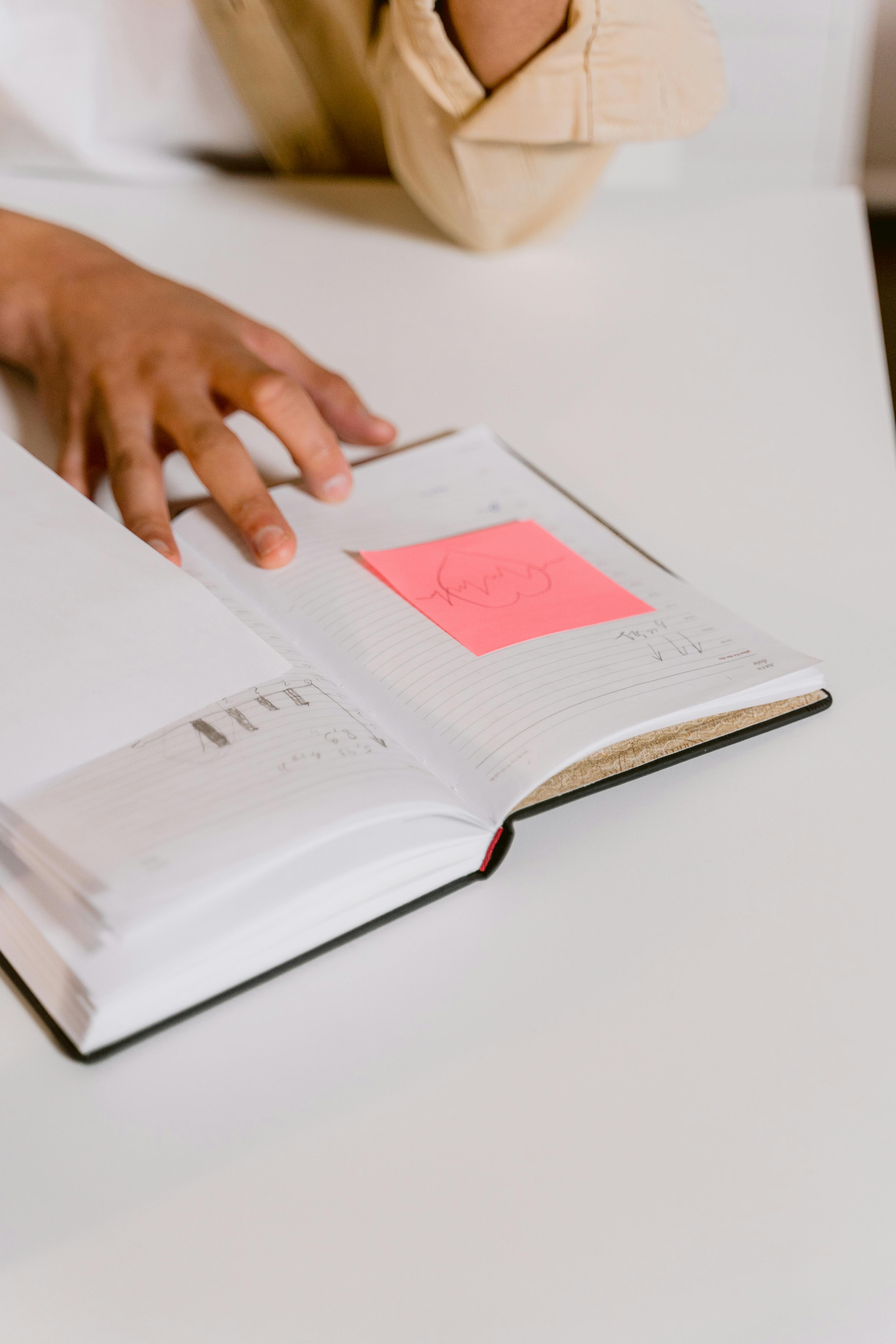 person holding white book on white table