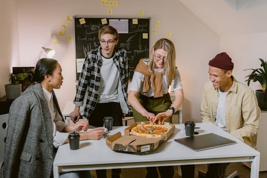 Diverse group of young professionals sharing a pizza in a modern office setting.