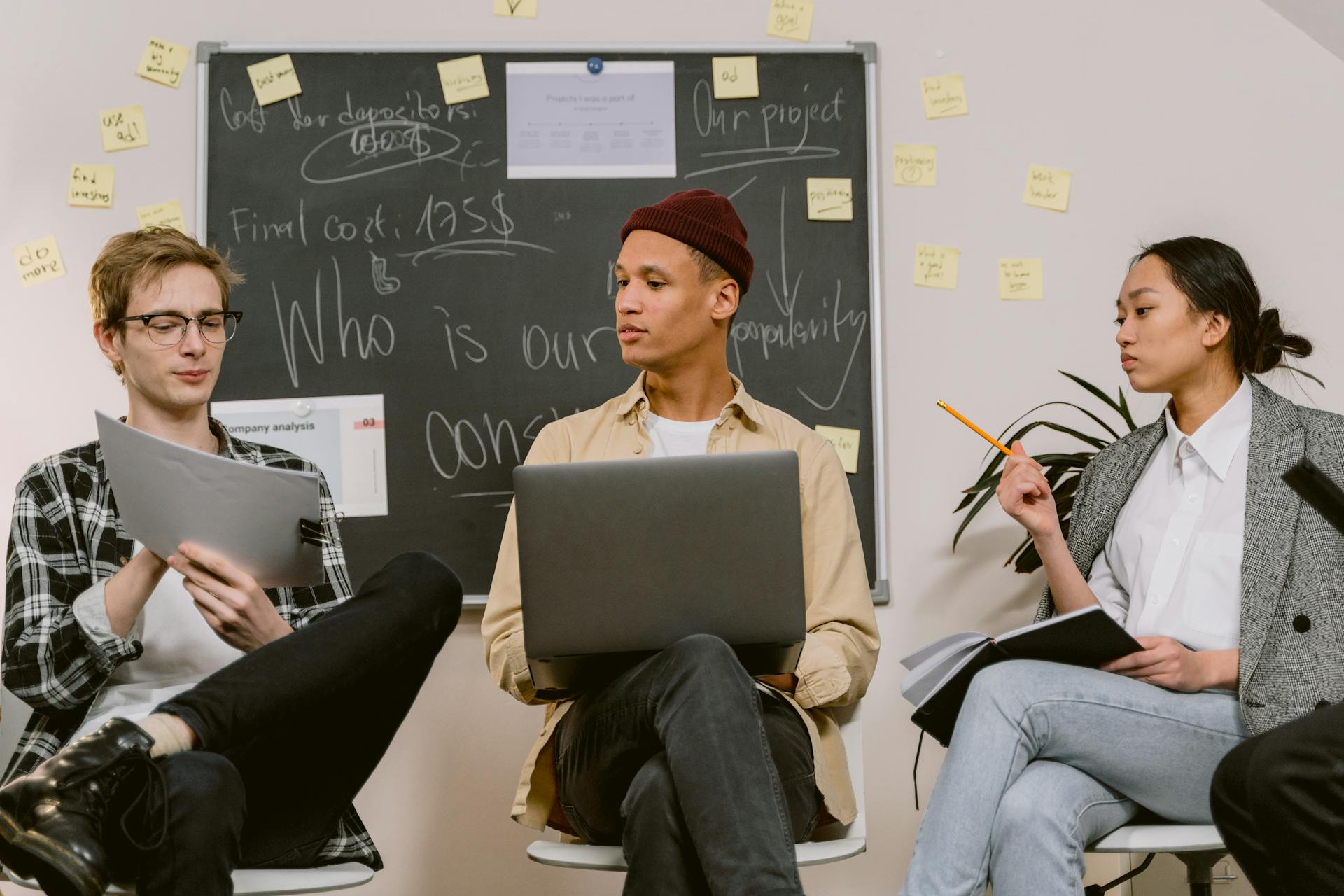 A diverse team collaborating in an office with laptops and notes, fostering teamwork and creativity.