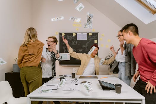 A joyful office team celebrates with money in the air, symbolizing success and teamwork.