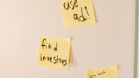Yellow sticky notes with motivational business ideas on a white wall.