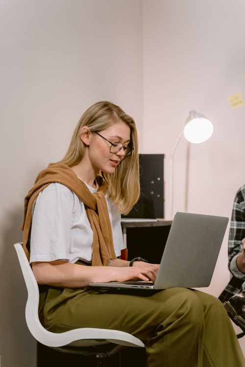 Free A young woman in casual attire works diligently on her laptop in a modern office setting. Stock Photo