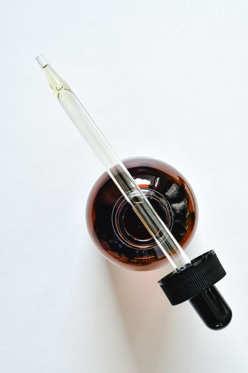 Free A glass pipette and amber bottle on a white surface, perfect for skincare and essential oil themes. Stock Photo