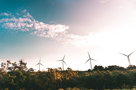 Wind turbines in a lush landscape generating renewable energy under a bright sky.