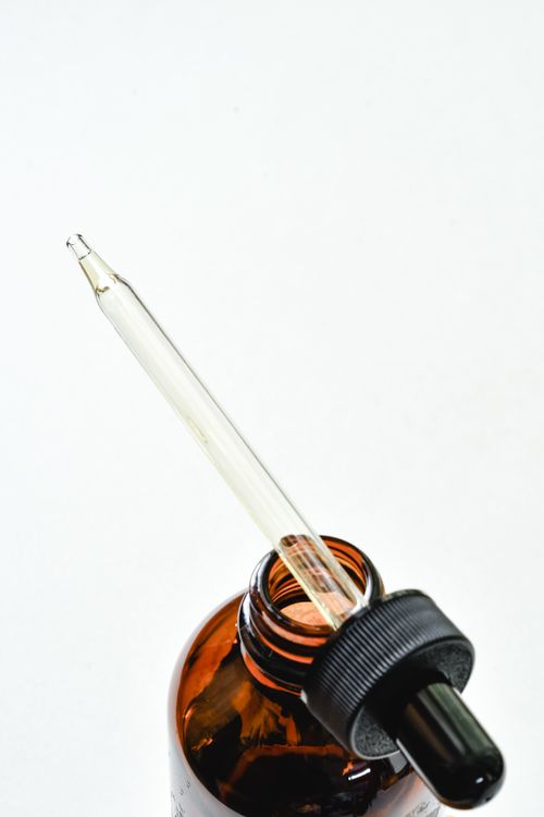 Free Close-up of a glass dropper in an amber bottle on a white background, perfect for skincare or aromatherapy themes. Stock Photo