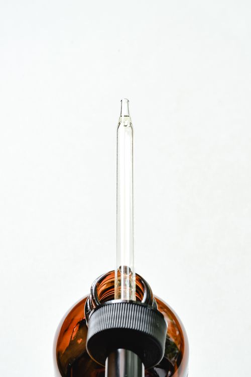Free Minimalist image of a glass dropper in an amber bottle, perfect for beauty or science themes. Stock Photo