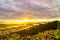 郁郁葱葱的丘陵与蜿蜒的河流间，日出令人惊叹，构成了一幅宁静的自然背景