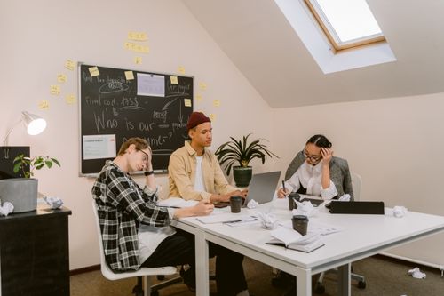 Free Young diverse team brainstorming ideas with laptops and notes in a modern office. Stock Photo