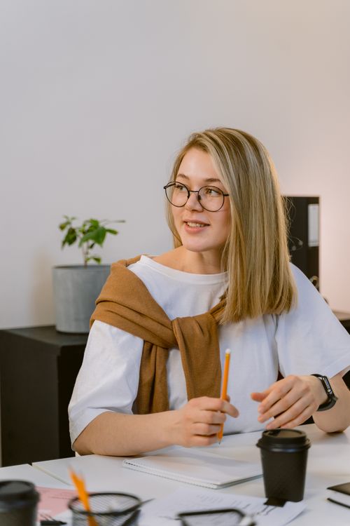 Free Professional young woman in office wearing glasses, engaging with a notepad. Stock Photo