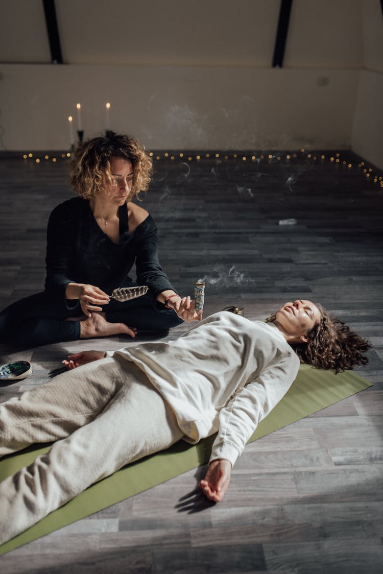 A Therapist Holding Healing Incense Near A Woman On A Yoga Mat