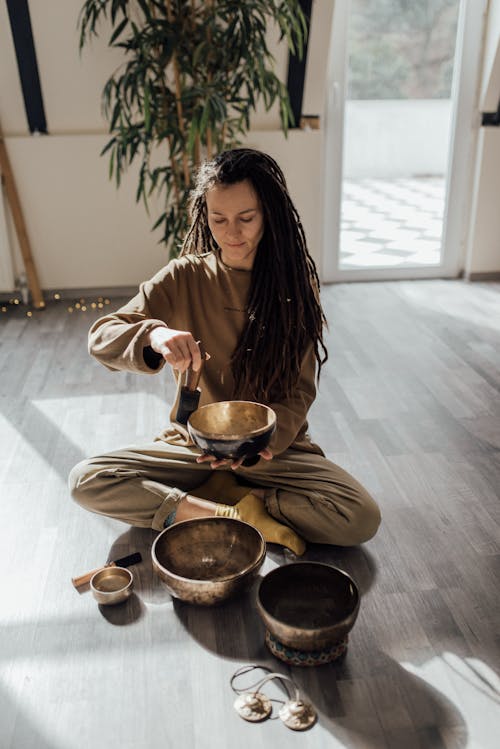 Woman in Brown Long Sleeves Holding Singing Bowls
