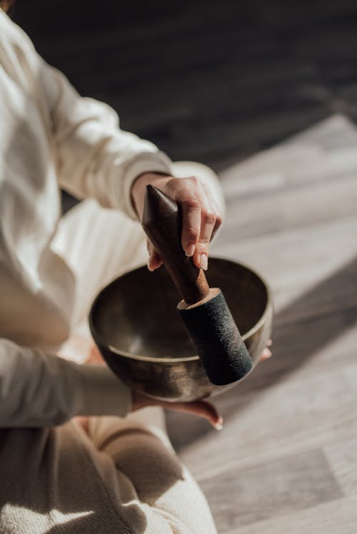 A Person Holding a Striker and Singing Bowl