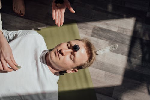 Free Man Lying Down on Floor with Healing Stone on Forehead Stock Photo