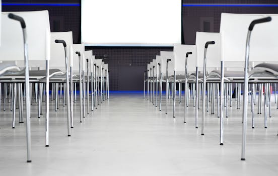 Empty modern conference room with white chairs in rows, ready for a presentation.