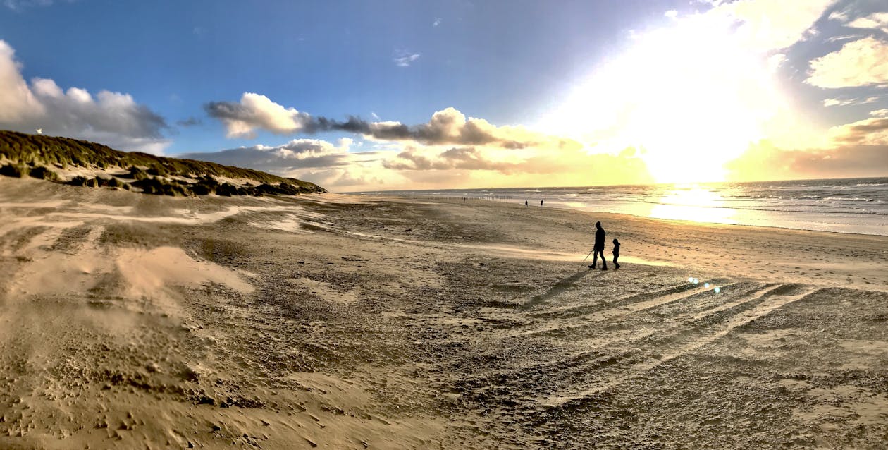 Photo of People Walking on Brown Sand