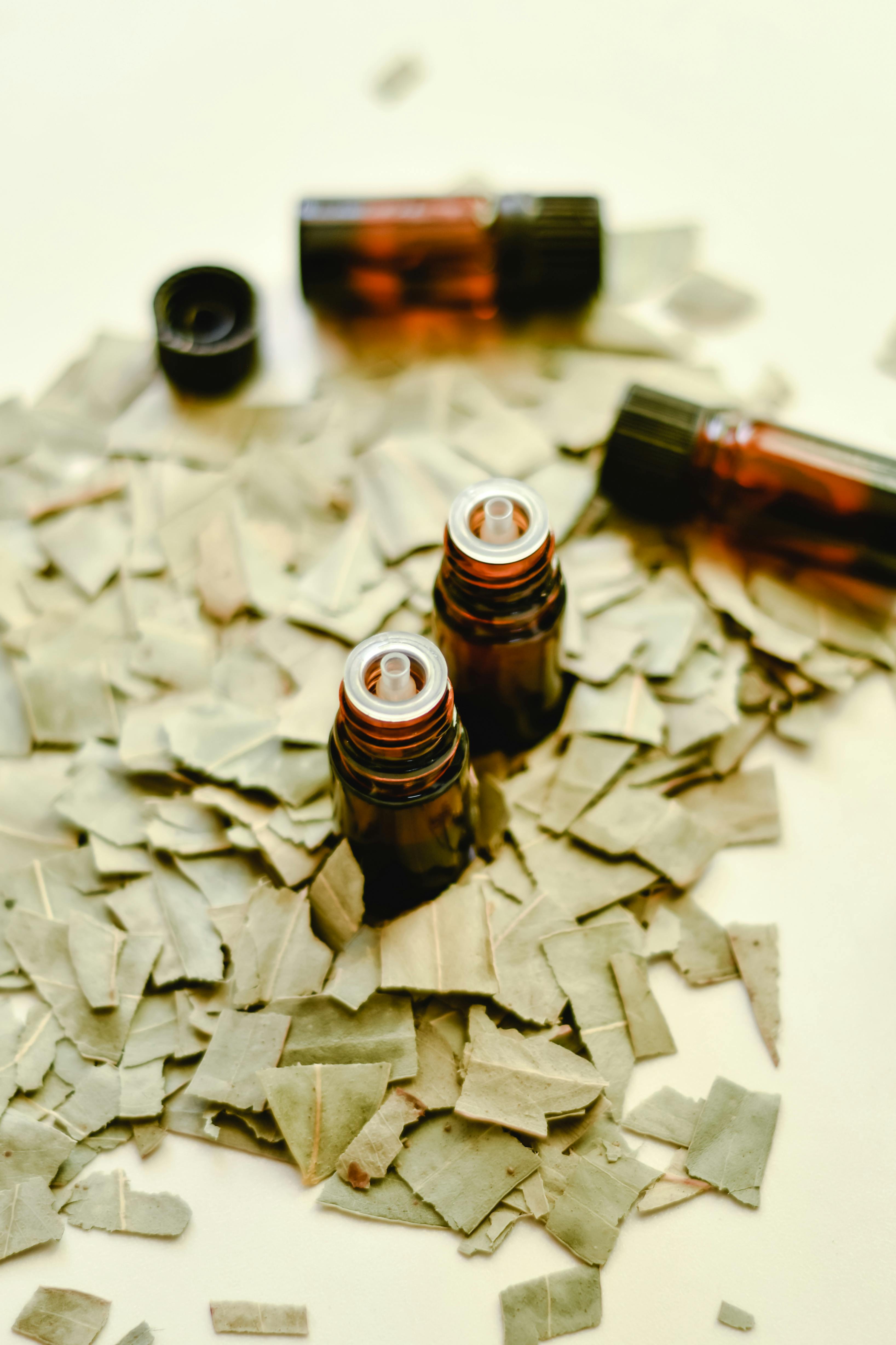 Close-up of essential oil bottles surrounded by dried leaves.