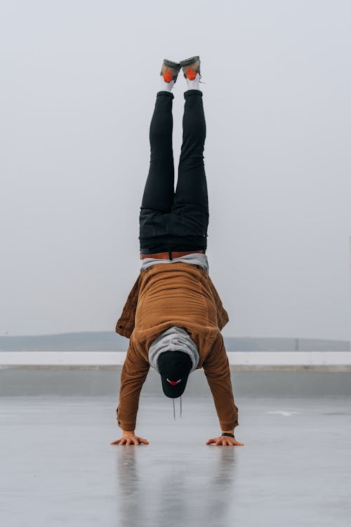 A Person in Black Pants and Brown Jacket Doing Hand Stand