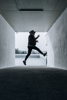 Dynamic silhouette of a man jumping mid-air in an urban tunnel setting.