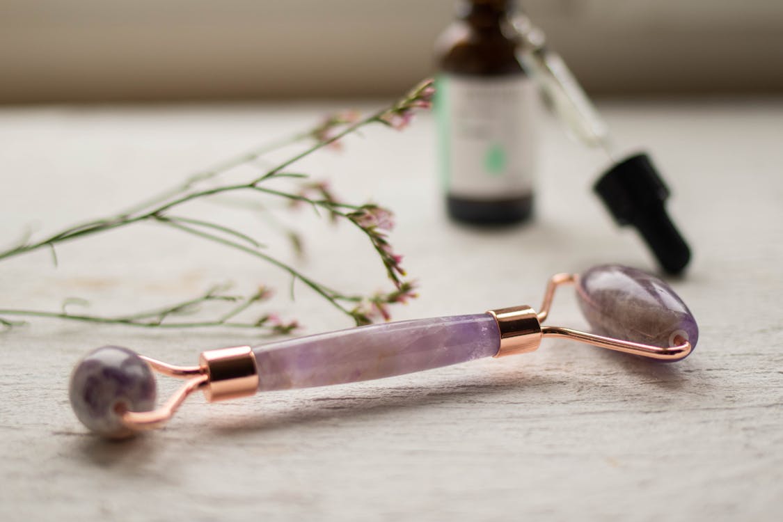 Close-Up Shot of an Amethyst Facial Roller on Wooden Surface 