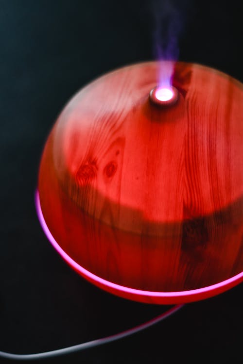 Close-Up Shot of a Red Essential Oil Diffuser on Black Surface