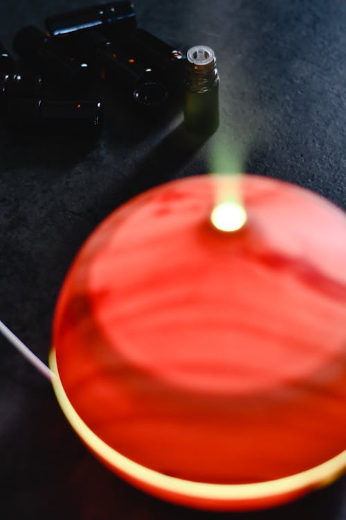 Close-Up Shot of a Red Essential Oil Diffuser on Black Surface