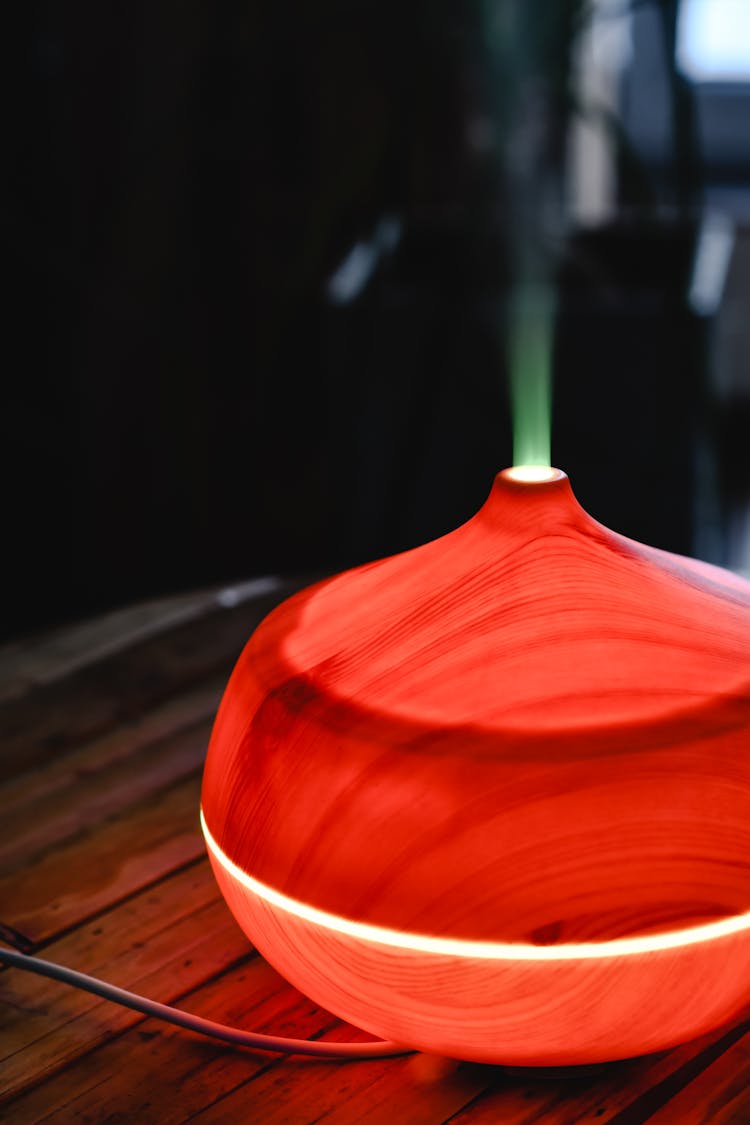 Close-Up Shot Of A Red Essential Oil Diffuser On Wooden Surface