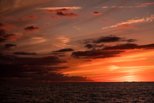Captivating sunset over the ocean with dramatic clouds and vibrant colors.