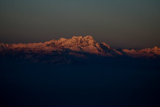 Breathtaking view of a snow-capped mountain range at twilight, showcasing nature's serene beauty.