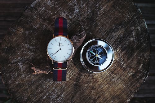 Круглые аналоговые часы серебристого цвета рядом с компасом