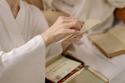 Person in White Long Sleeve Shirt Holding White Paper