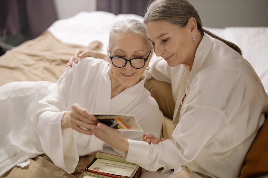 Senior women in bathrobes bonding over cherished photo memories indoors.