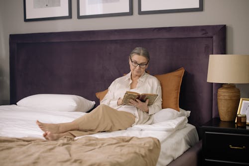 Free Elderly Woman Sitting on Bed While Reading a Book Stock Photo
