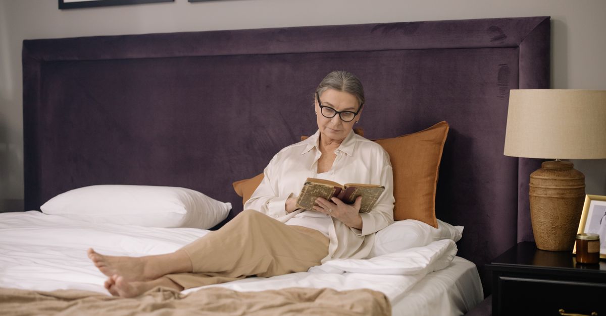 Vrouw leest een boek in bed bij warm licht