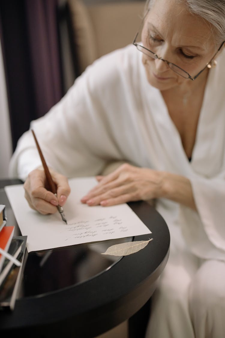 An Elderly Woman Writing On The Paper