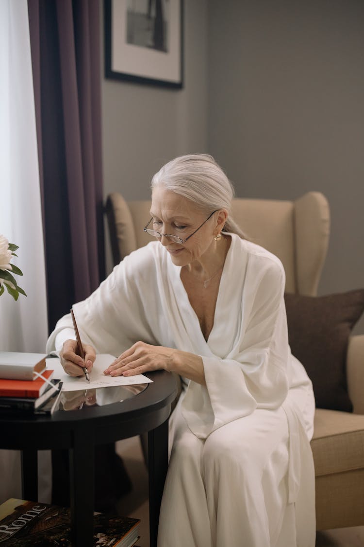 Elderly Woman In White Robe Writing With A Fountain Pen