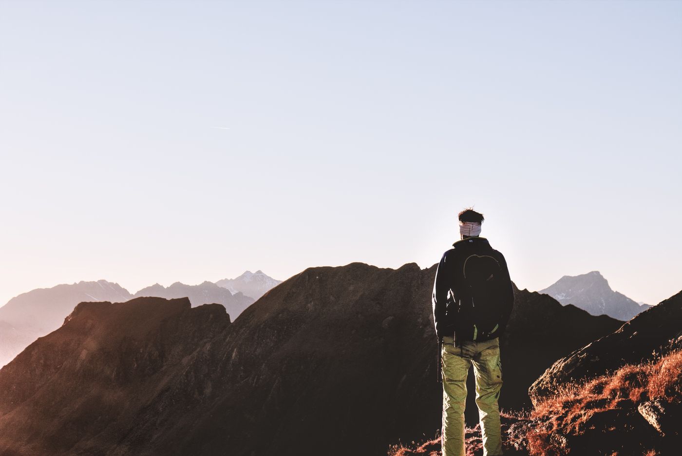 A lone hiker standing on a rocky mountain peak above the clouds