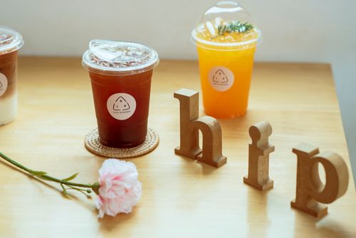 Free Refreshing cold drinks in plastic cups on a wooden table with decorative letters and a pink carnation. Stock Photo