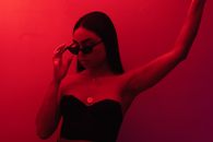 Stylish ethnic woman in sunglasses standing in studio
