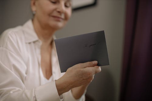 A Woman Wearing White Clothes Holding a Letter Envelope