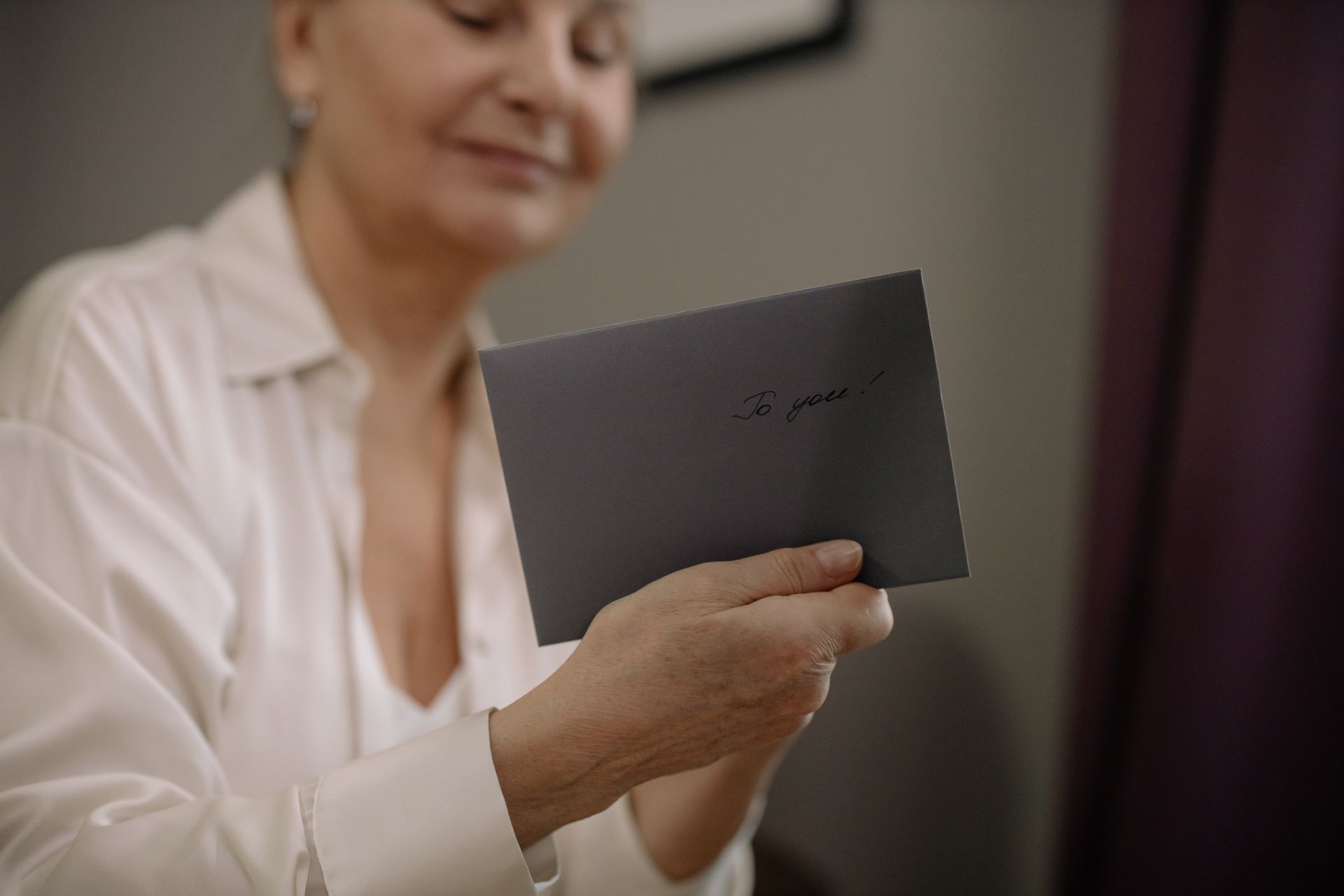 An elderly woman holds a heartfelt letter. The envelope reads 'To you' in elegant handwriting.