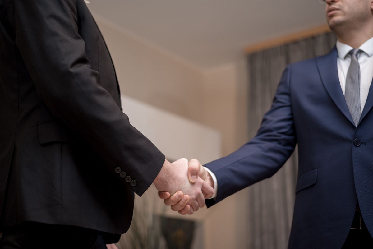 Two business executives shaking hands in professional suits