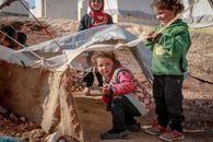 Carefree ethnic preschool children playing in rustic yard with rubbish in settlement of refugee