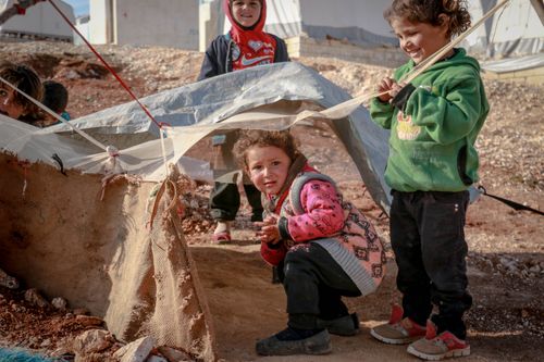 Free Carefree ethnic preschool children playing in rustic yard with rubbish in settlement of refugee Stock Photo