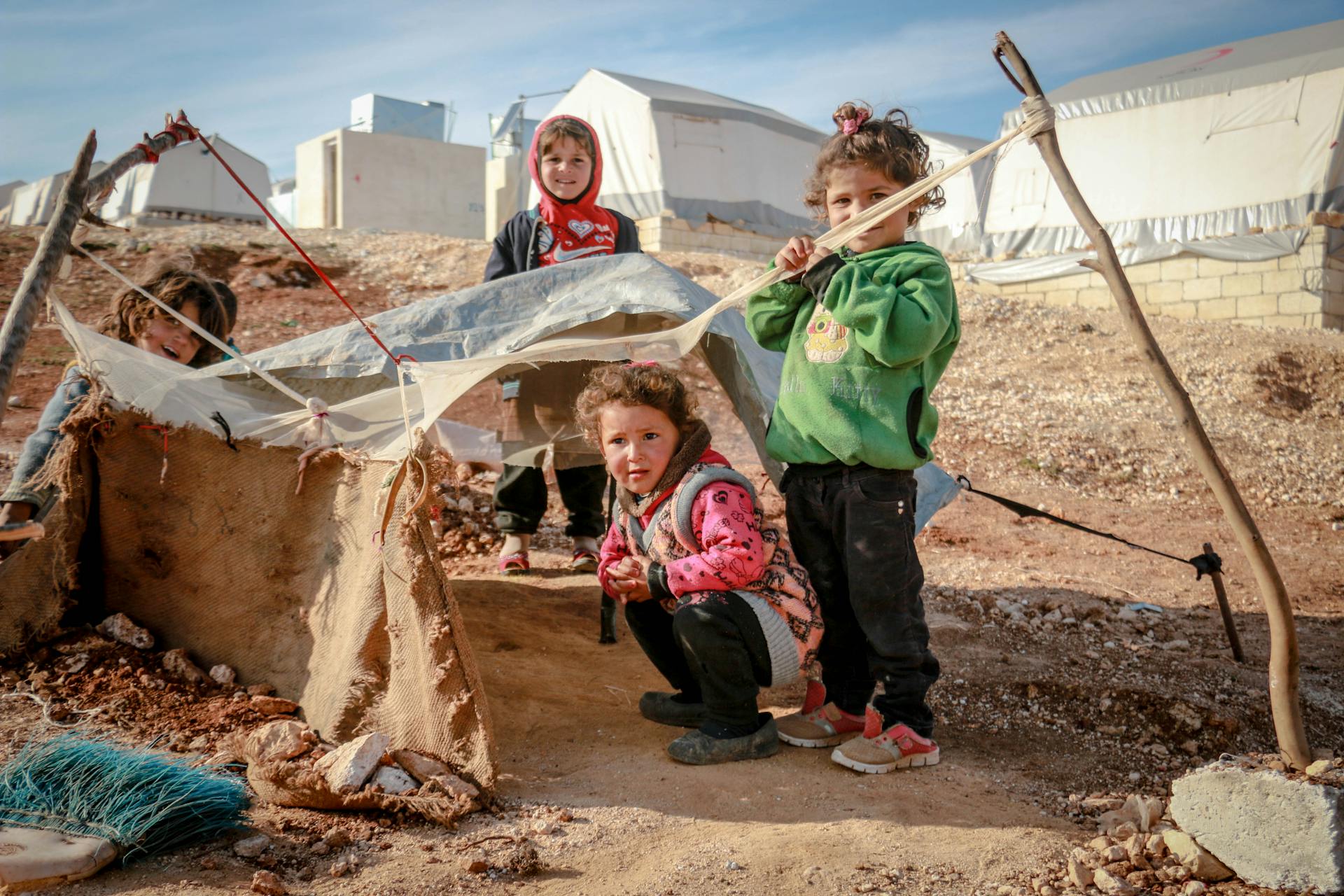 Children play with makeshift tents in a Syrian refugee camp, capturing their innocence and resilience.