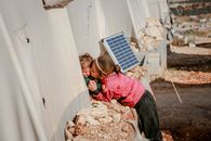 Ethnic girl kissing brother outside refugee tents