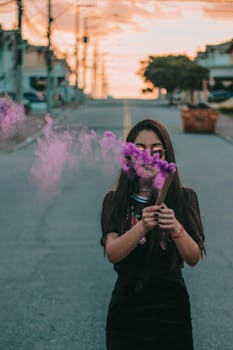 日落时分，一名妇女在空旷的城市街道上举起紫色烟雾，营造出戏剧性的场面