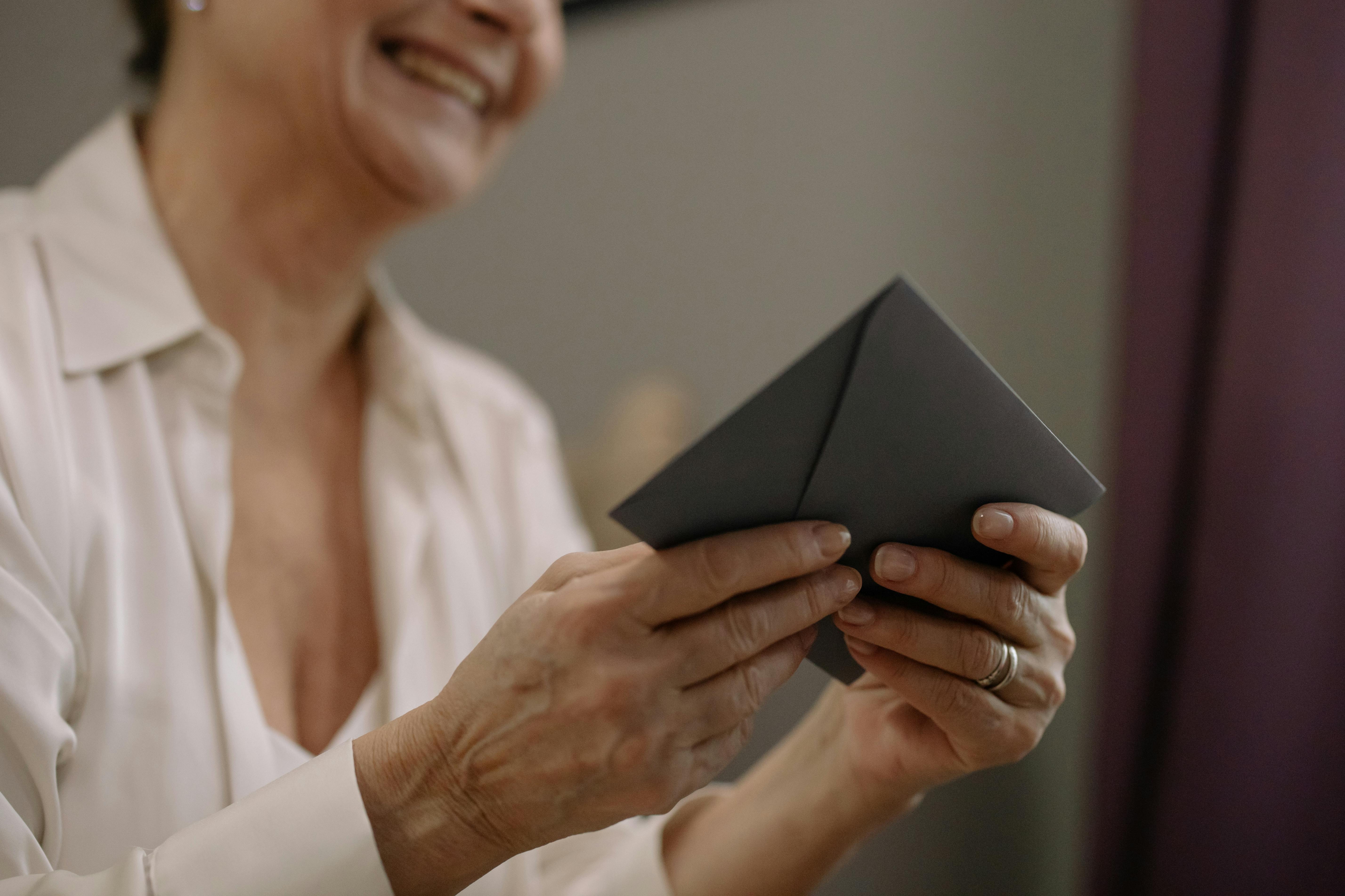 an elderly person holding a black envelope