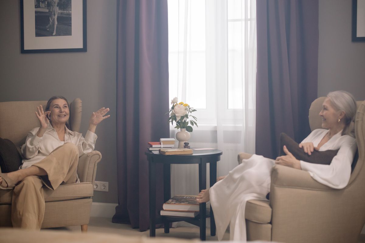 Two senior friends sharing a conversation in a comfortable living room