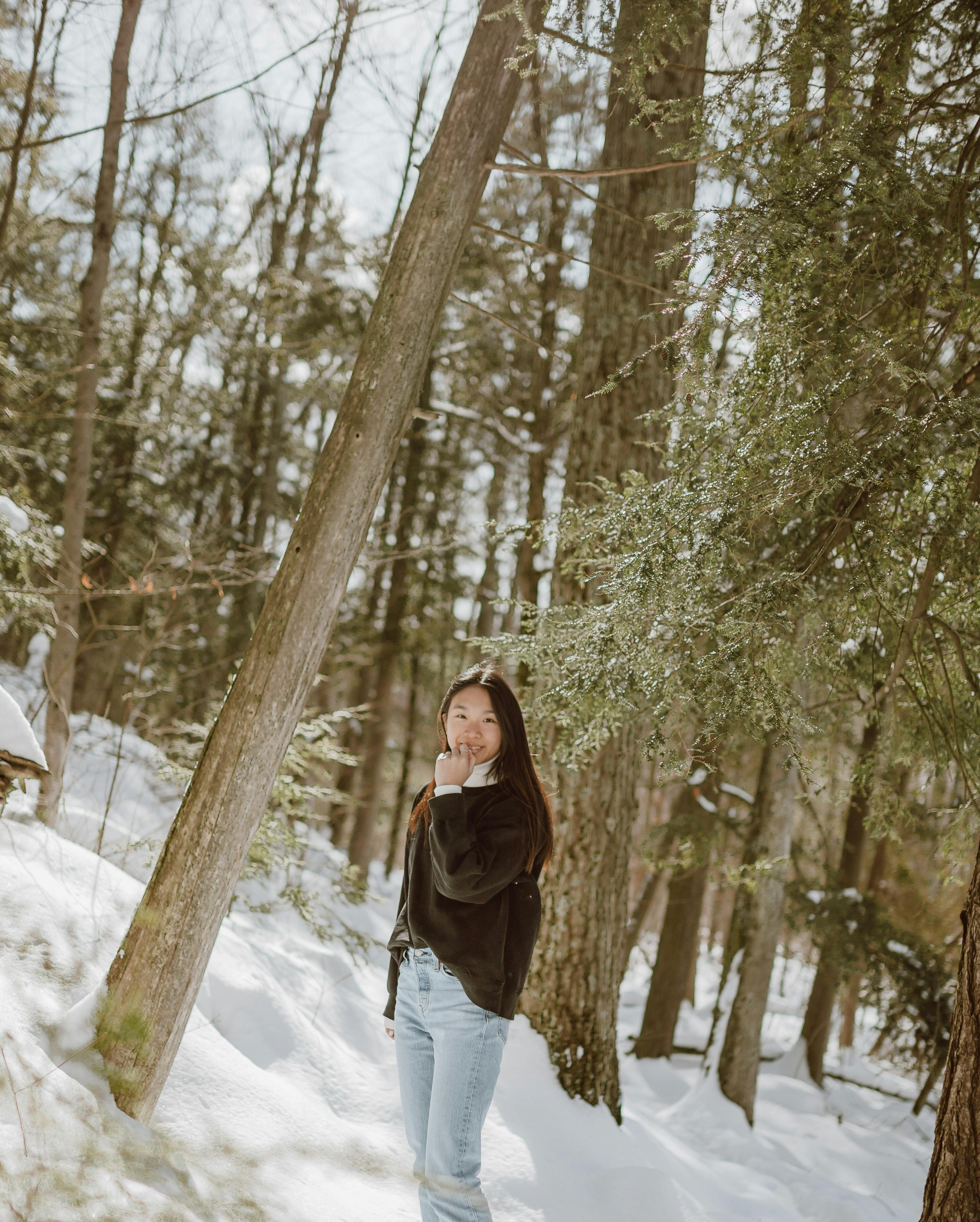 Smiling female walking on road among snowy forest · Free Stock Photo